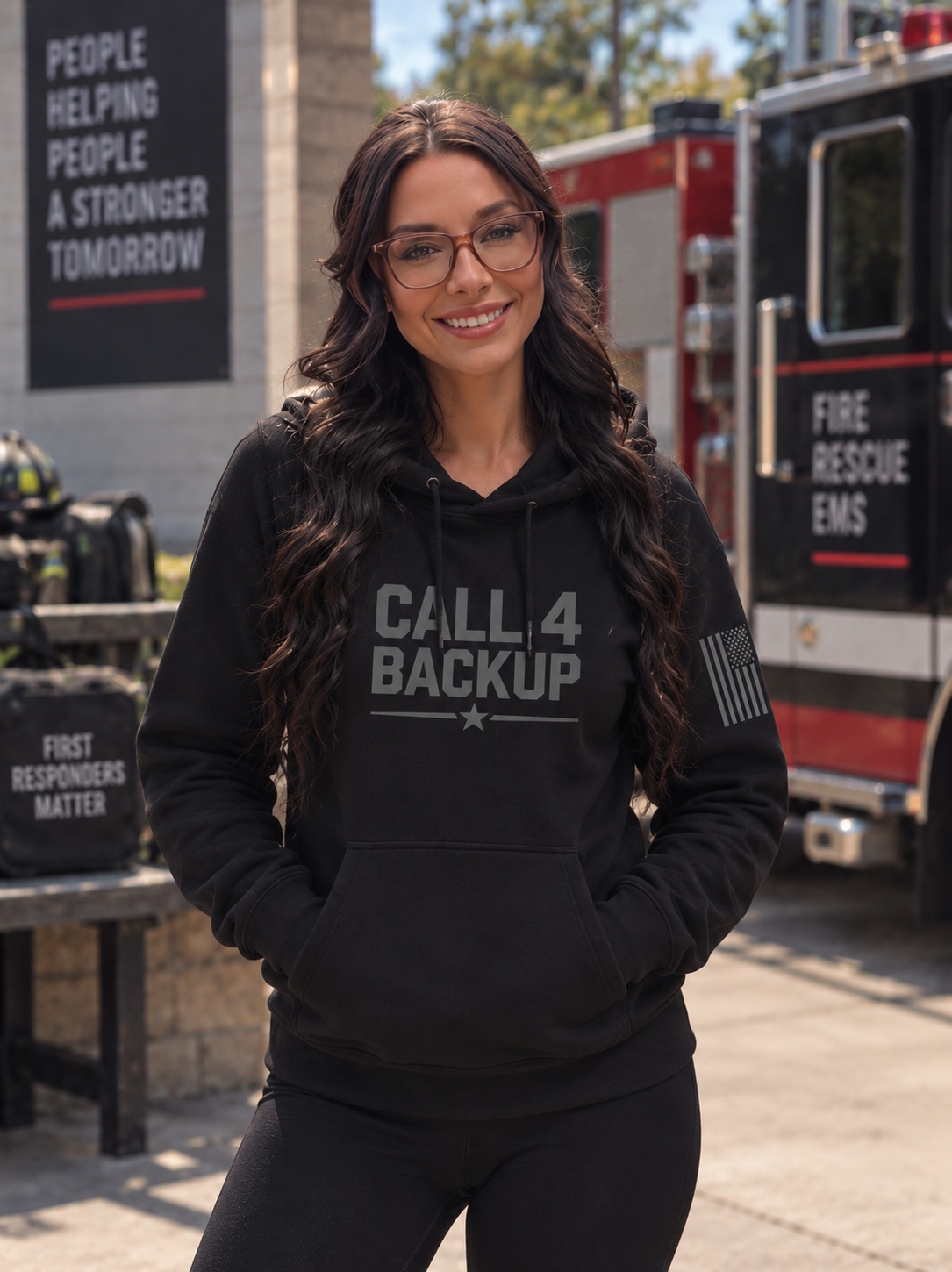 Supplied apparel mockup of a woman in a black Call 4 Backup hoodie beside a fire engine.